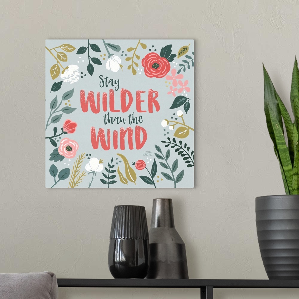 A modern room featuring "Stay Wilder Than The Wind" framed by wild flowers on a gray background.