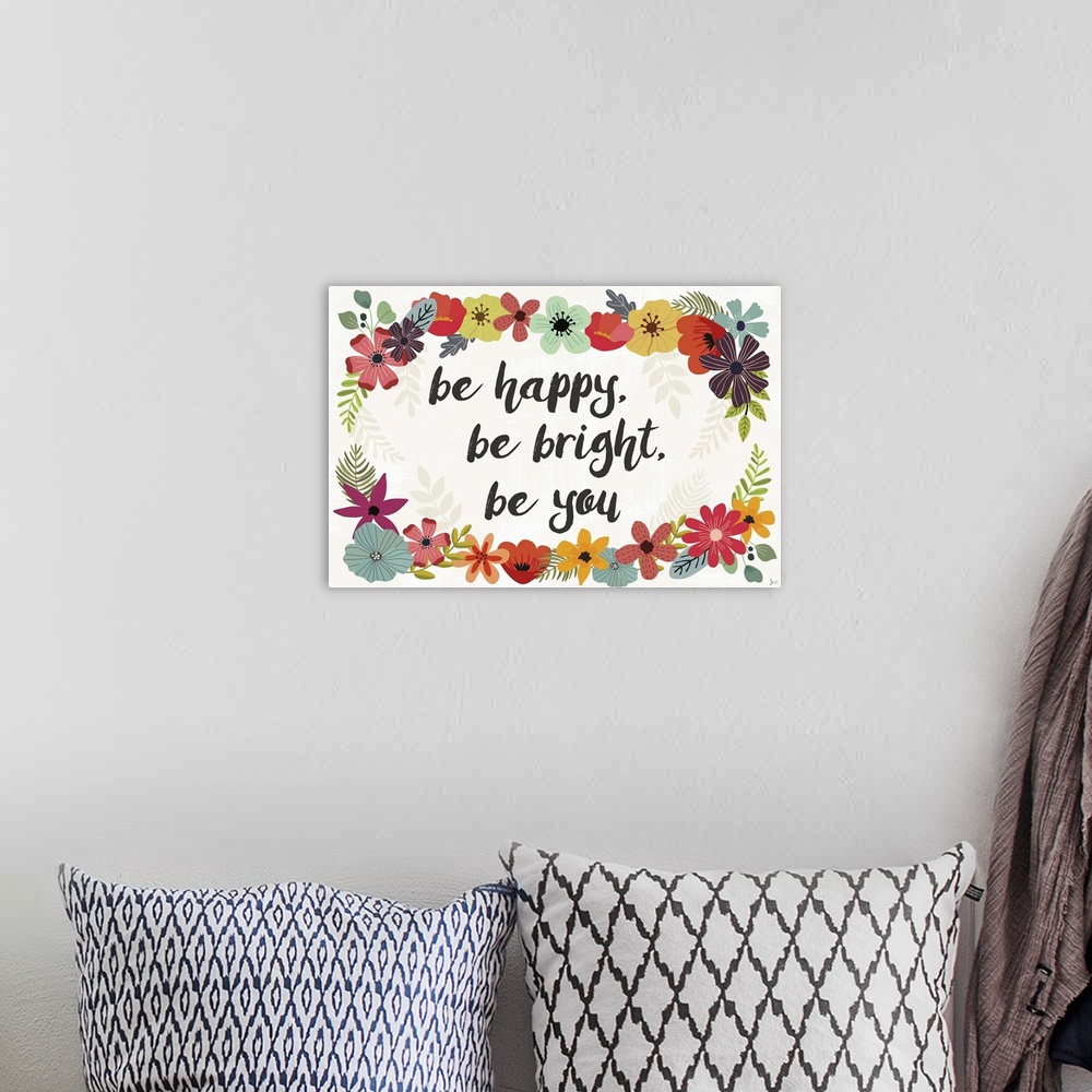 A bohemian room featuring "Be Happy, Be Bright, Be You" written in the center of a colorful floral wreath.