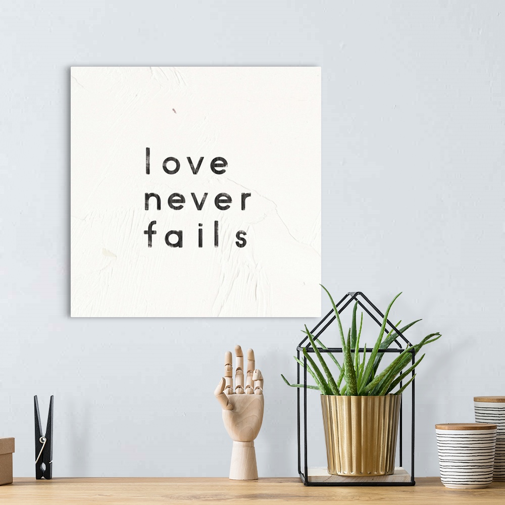 A bohemian room featuring "Love Never Fails" written on a painted white texture background.
