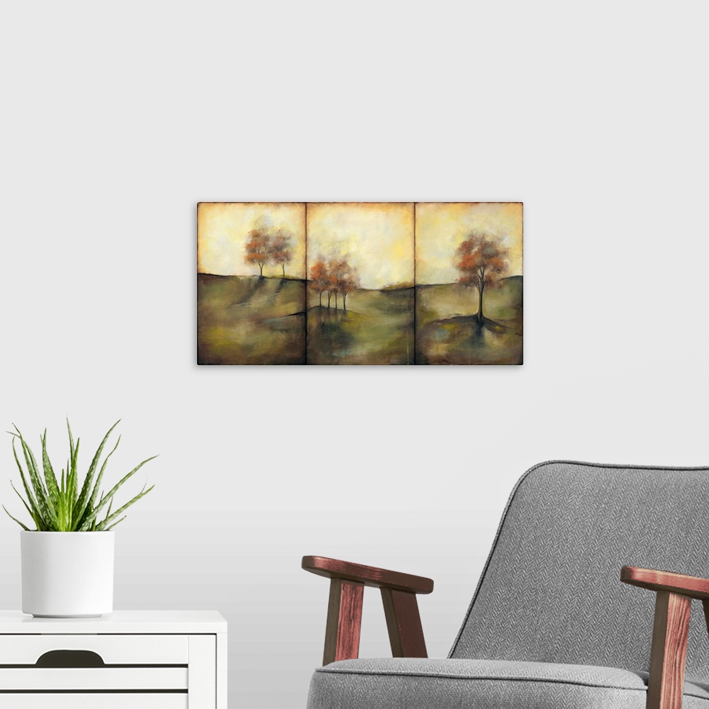 A modern room featuring Triptych painting of a countryside meadow in the fall, with small groups of trees.