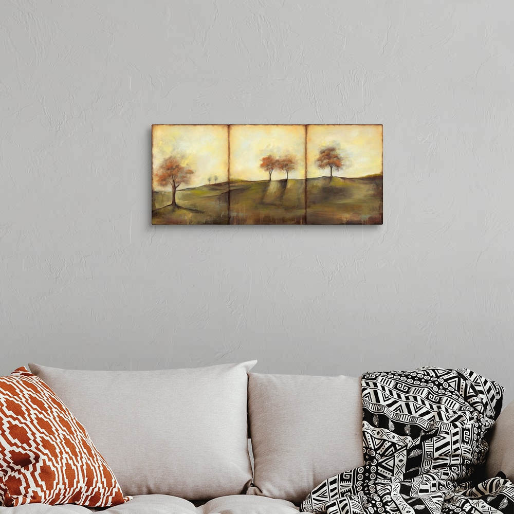 A bohemian room featuring Triptych painting of a countryside meadow in the fall, with small groups of trees.