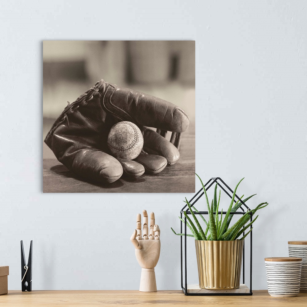 A bohemian room featuring Square sepia toned photograph of a worn baseball in a vintage mitt on a soft focus backdrop.