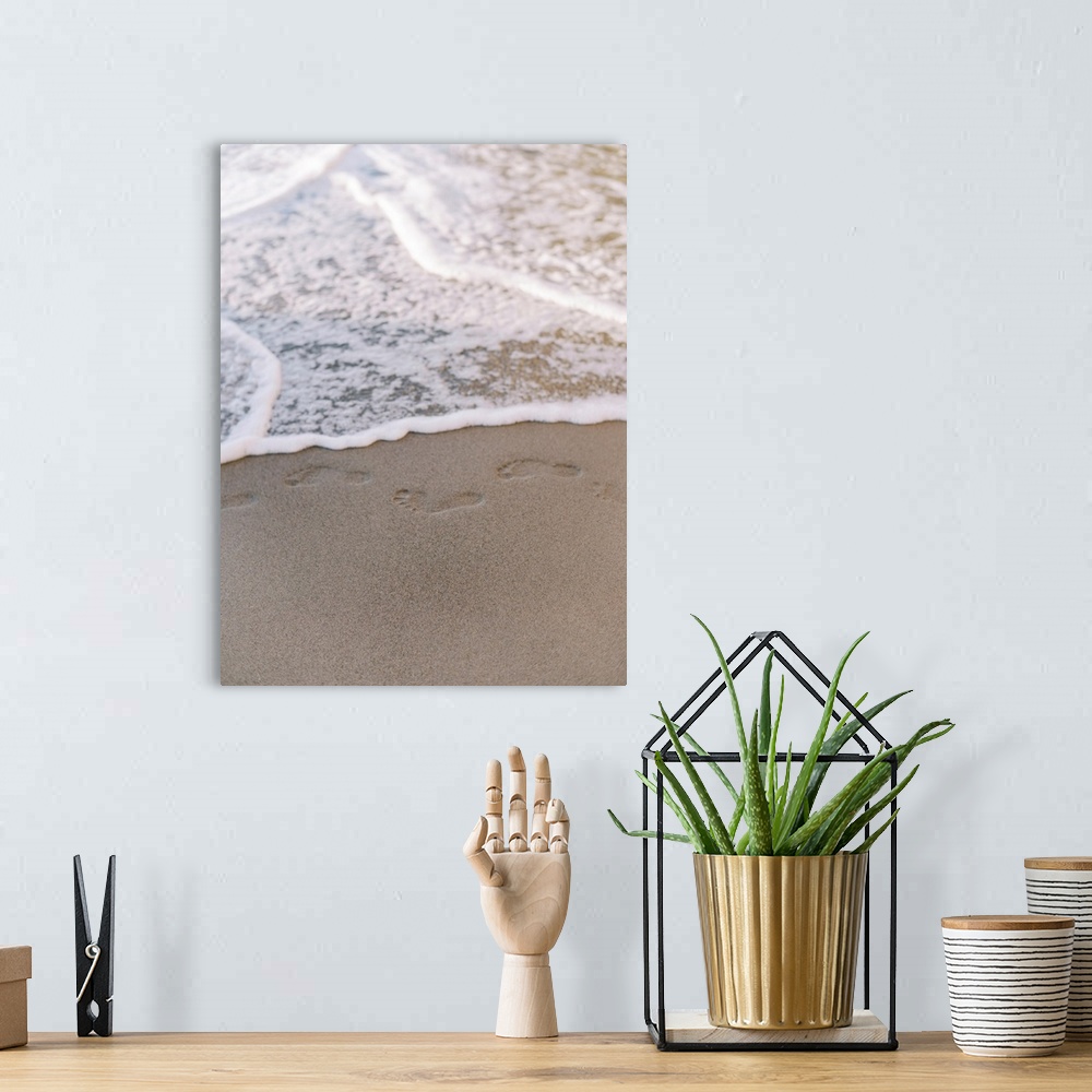 A bohemian room featuring A photograph of small footprints in the sand about to be lapped with gentle waves.