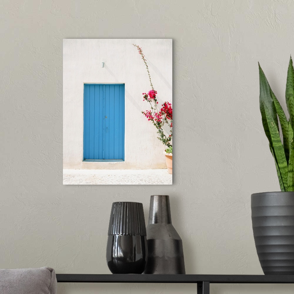 A modern room featuring Photograph of a simple, rustic blue door in a mediterranean building, with a planter of tall pink...