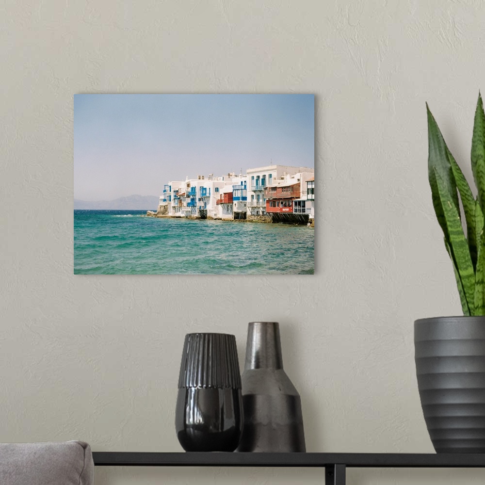 A modern room featuring Photograph of white buildings with colorful balconies overlooking the water in Mykonos, Greece.