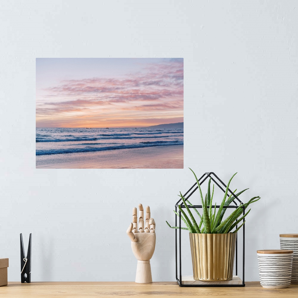 A bohemian room featuring A photograph of gentle waves lapping the beach under an early evening sky where the sun is beginn...