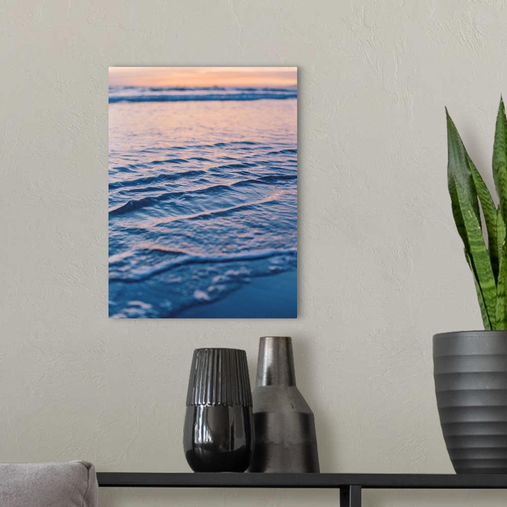 A modern room featuring A close up photograph of gentle waves lapping the beach under an early evening sky where the sun ...