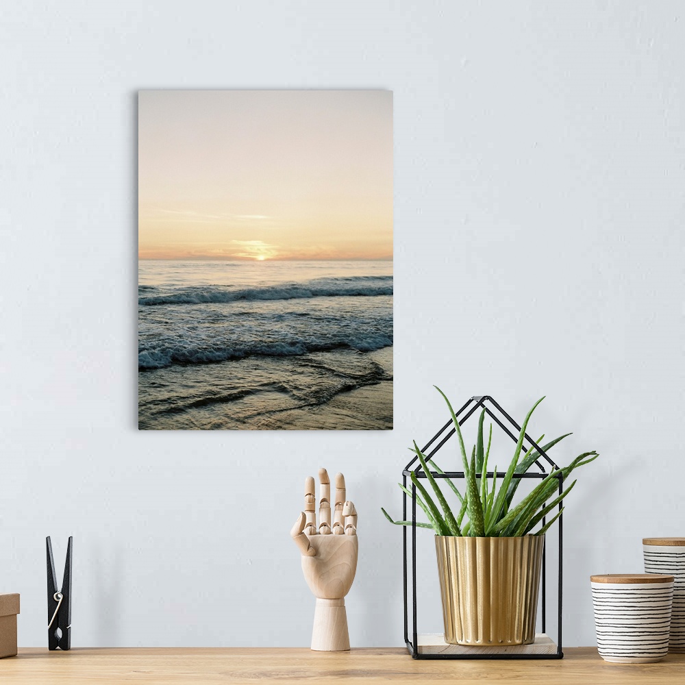 A bohemian room featuring A photograph of gentle waves lapping the beach under an early evening sky where the sun is beginn...