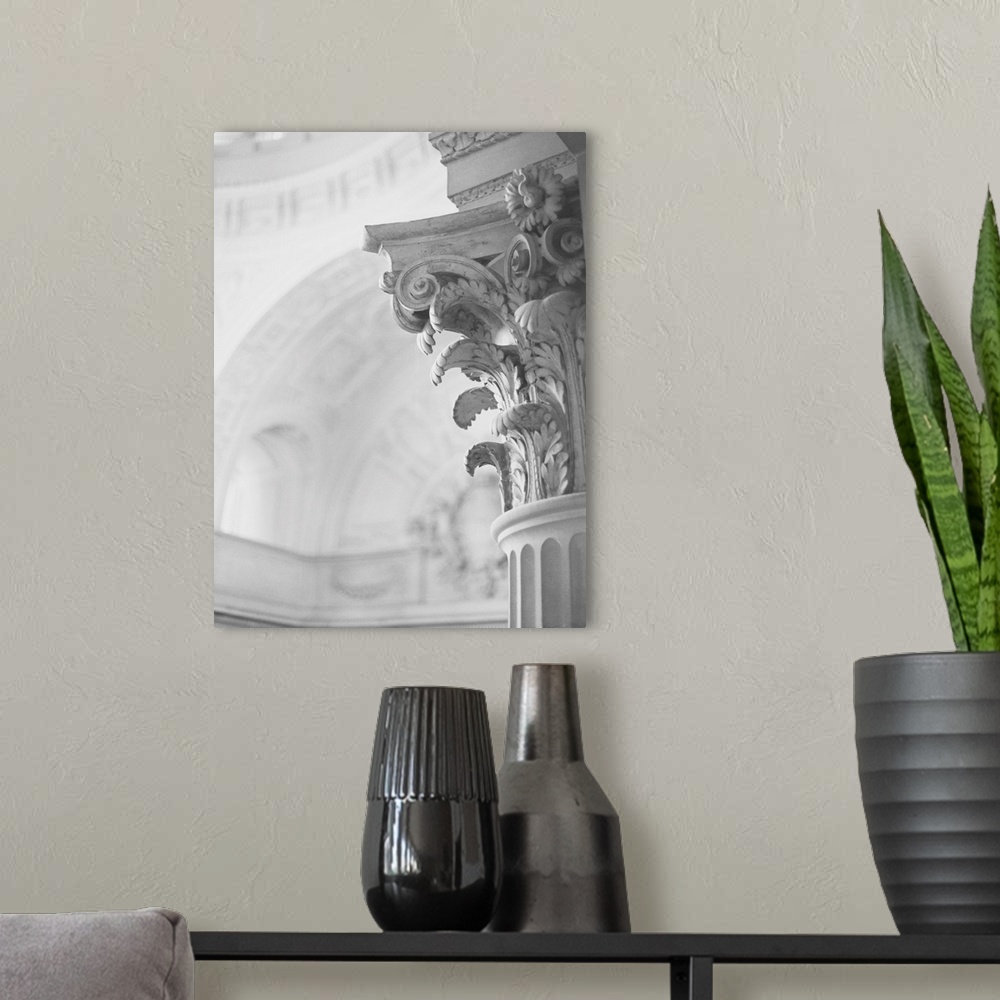A modern room featuring A black and white photograph of the detail of an architectural column featuring scrolls, daisies ...