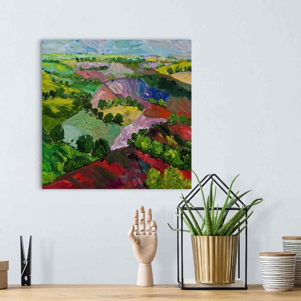 A bohemian room featuring Contemporary painting of a country landscape with colorful hills and rows of trees.