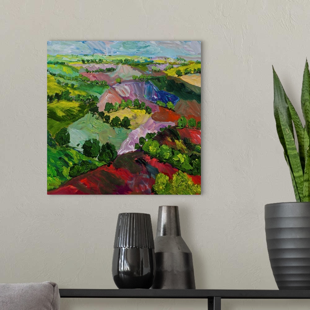 A modern room featuring Contemporary painting of a country landscape with colorful hills and rows of trees.