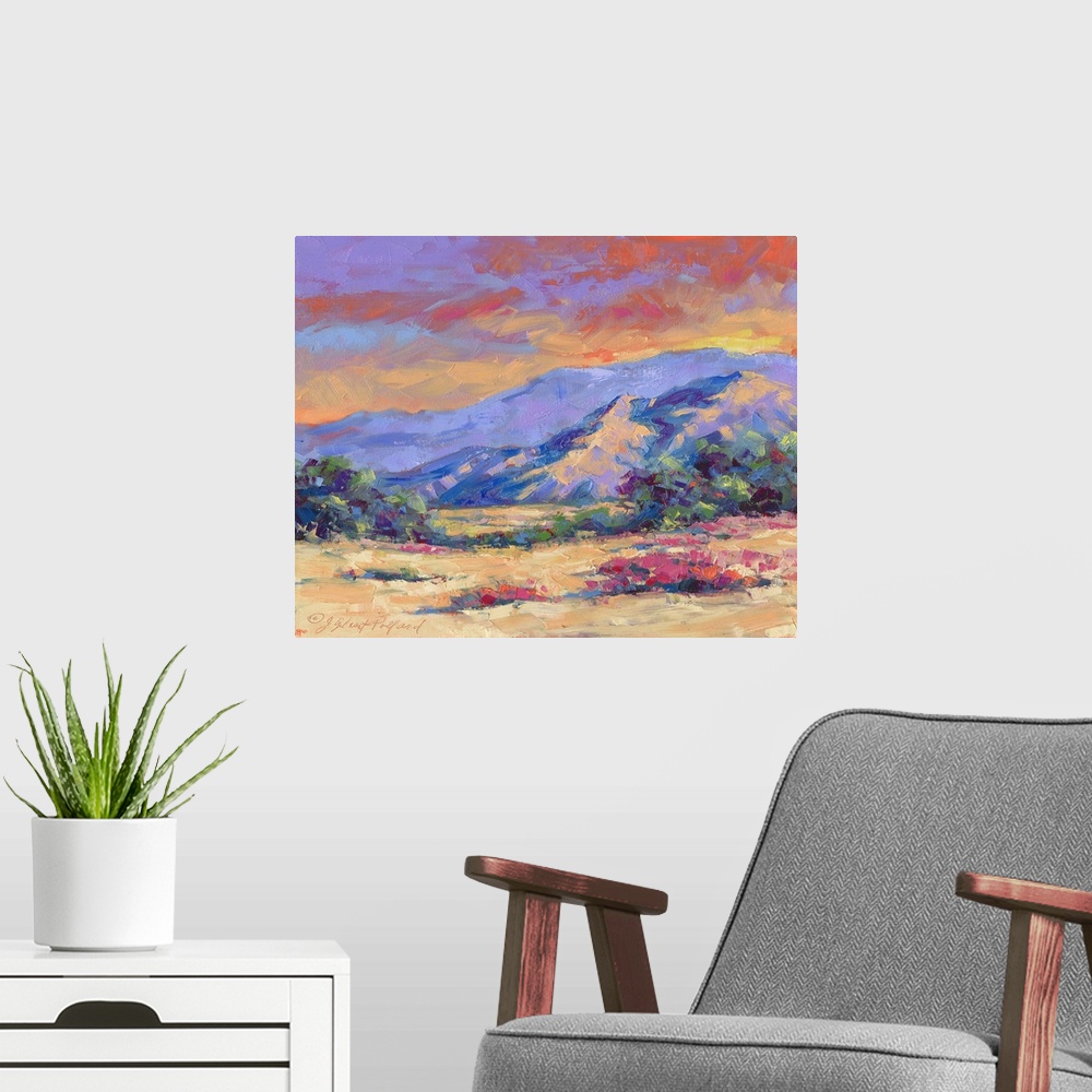 A modern room featuring Contemporary vibrant landscape painting of a desert mountain sunset.