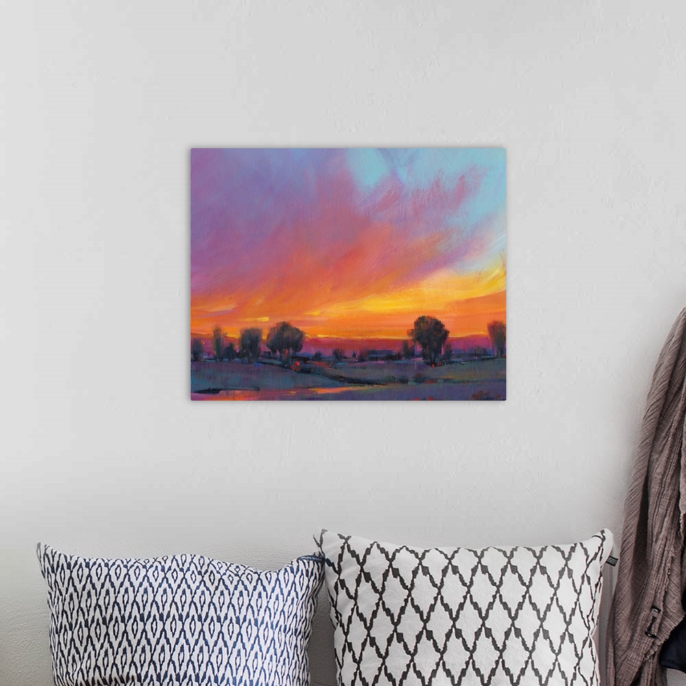 A bohemian room featuring Contemporary painting with vibrant oranges and yellows of a sun setting over the countryside.