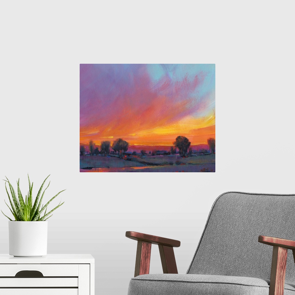 A modern room featuring Contemporary painting with vibrant oranges and yellows of a sun setting over the countryside.