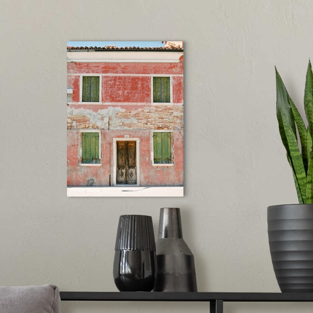 A modern room featuring Photograph of a very old building with green shutters and pink walls, Burano, Italy.