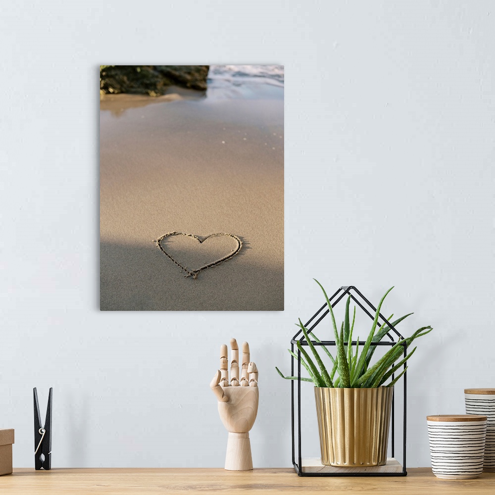 A bohemian room featuring A photograph of a simple heart shape carved into otherwise untouched sand at the edge of the ocean.