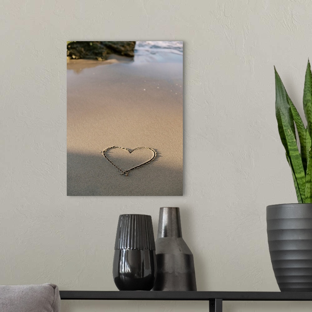 A modern room featuring A photograph of a simple heart shape carved into otherwise untouched sand at the edge of the ocean.