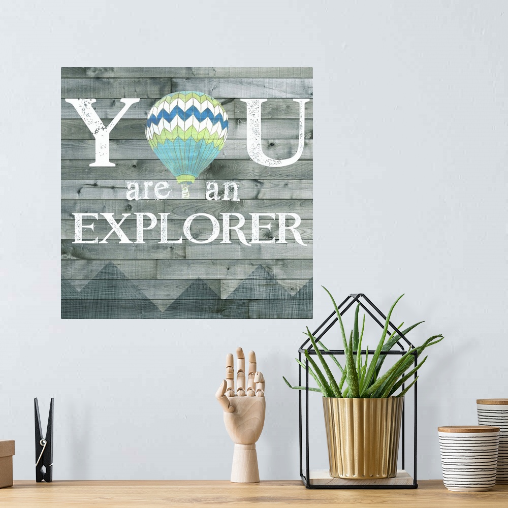 A bohemian room featuring Inspirational decorative artwork of the phrase "You are an explorer" with a hot air balloon design.