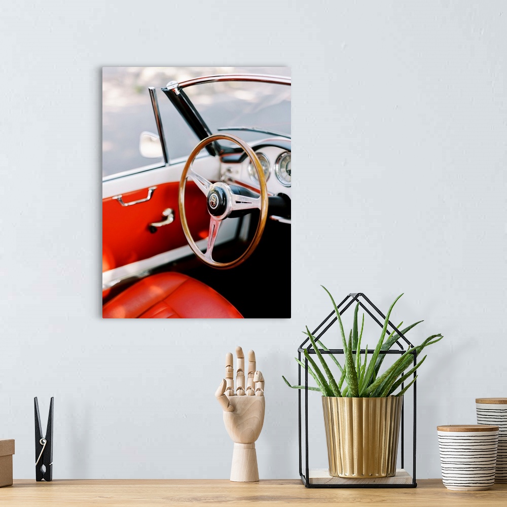 A bohemian room featuring A photograph of the steering wheel and interior of an antique convertible sports car with red lea...