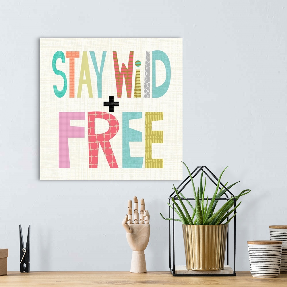 A bohemian room featuring Children's typography artwork in colorful block letters reading "Stay Wild and Free."