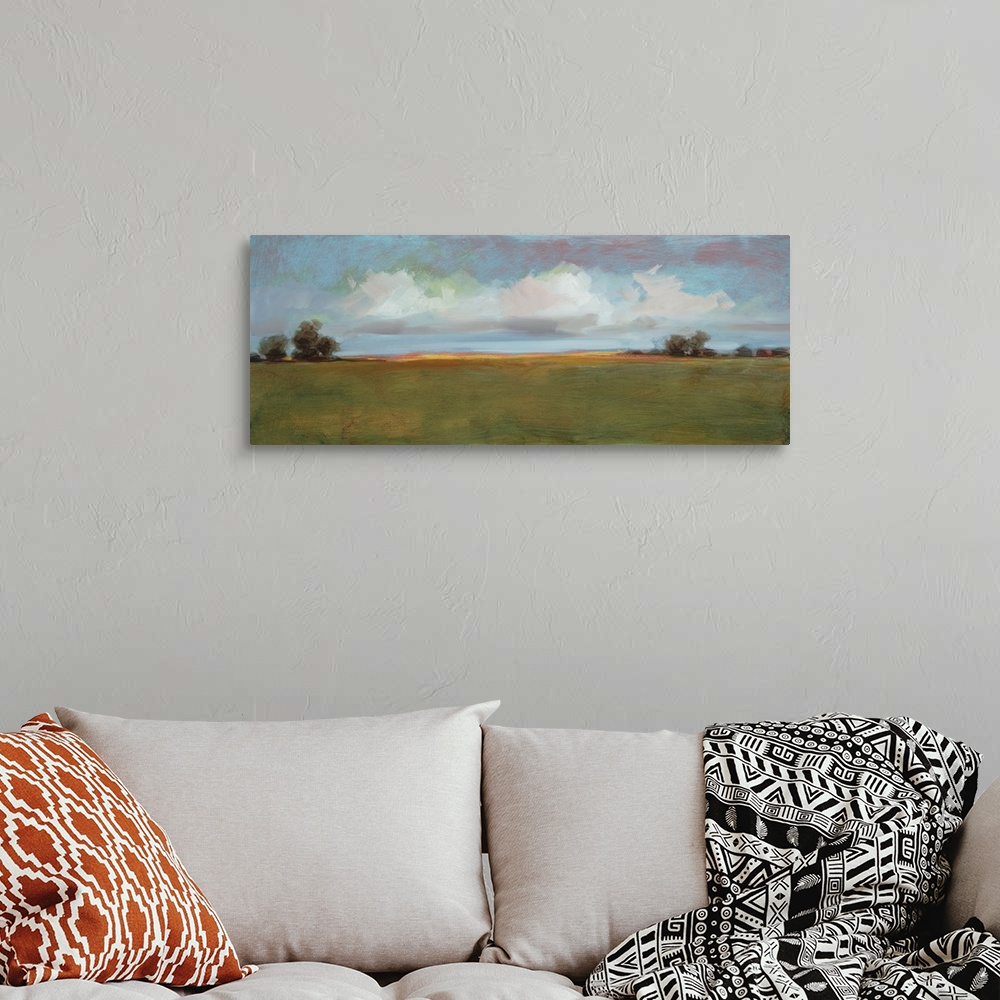 A bohemian room featuring Contemporary landscape artwork of an open field with sparse trees under a cloudy sky.