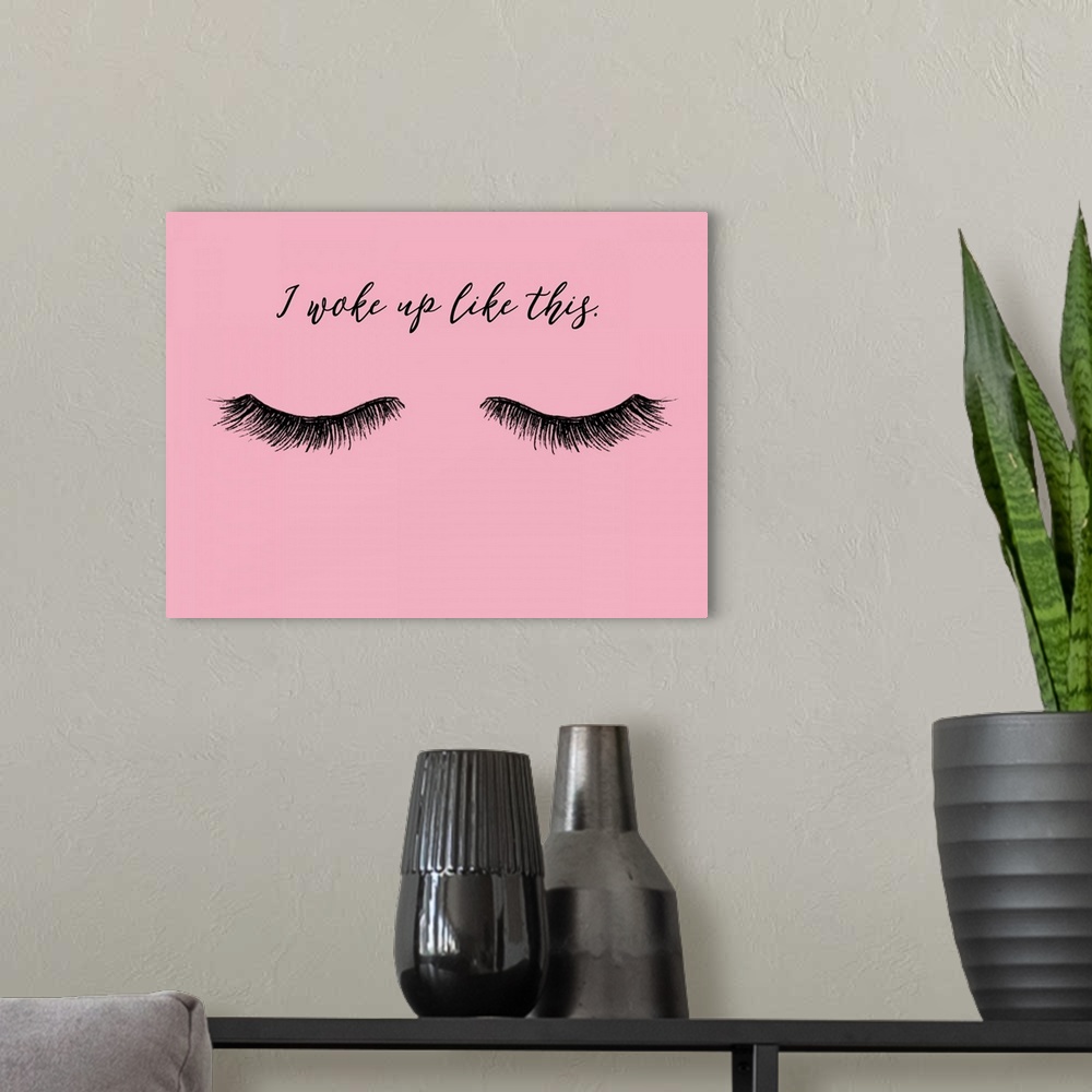 A modern room featuring "I Woke Up Like This" with eyelashes in black on a pink background.