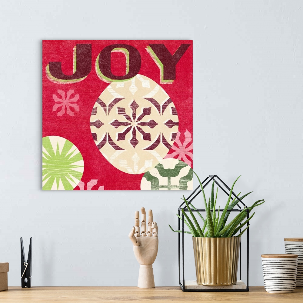 A bohemian room featuring "Joy" surrounded by holiday ornaments against a red backdrop and overlapping thin white lines tha...
