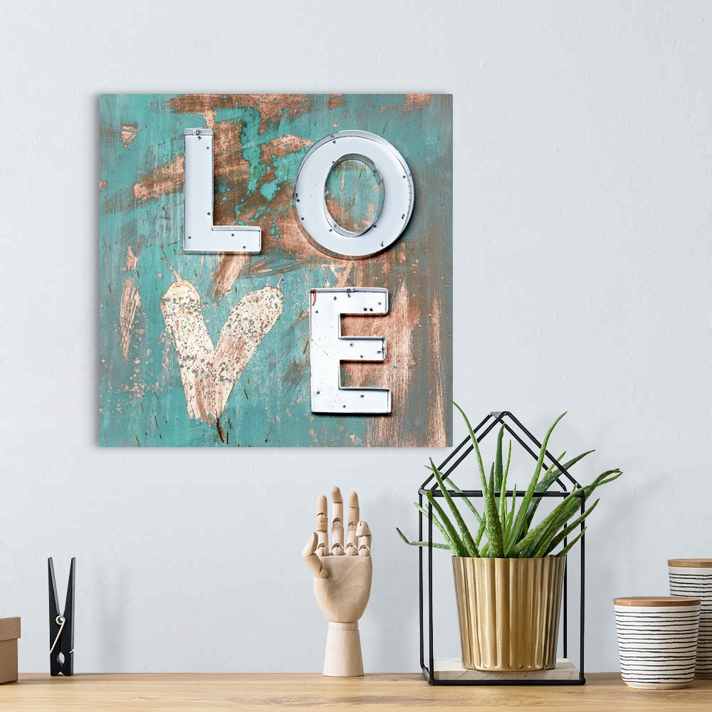 A bohemian room featuring The word "Love" made of metal letters and a painted heart on weathered teal boards.