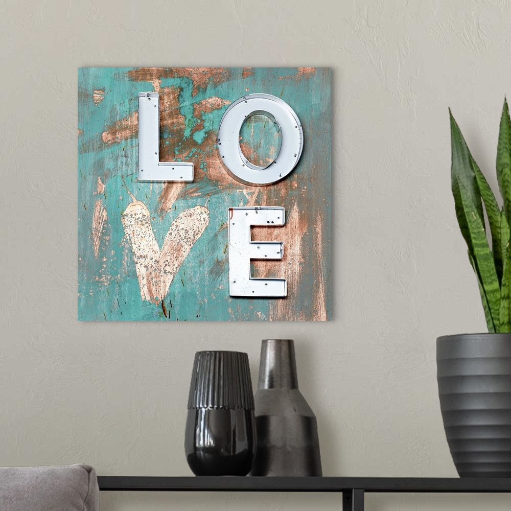 A modern room featuring The word "Love" made of metal letters and a painted heart on weathered teal boards.
