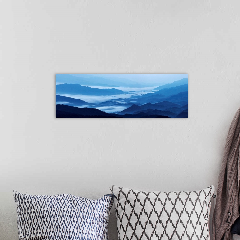 A bohemian room featuring Panoramic landscape photograph of blue mountains covered in fog.
