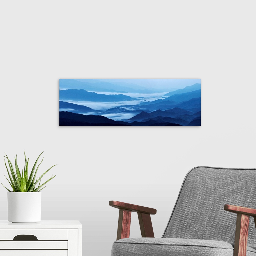 A modern room featuring Panoramic landscape photograph of blue mountains covered in fog.