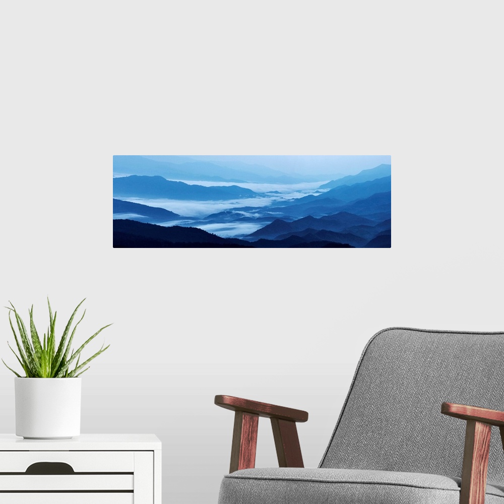 A modern room featuring Panoramic landscape photograph of blue mountains covered in fog.