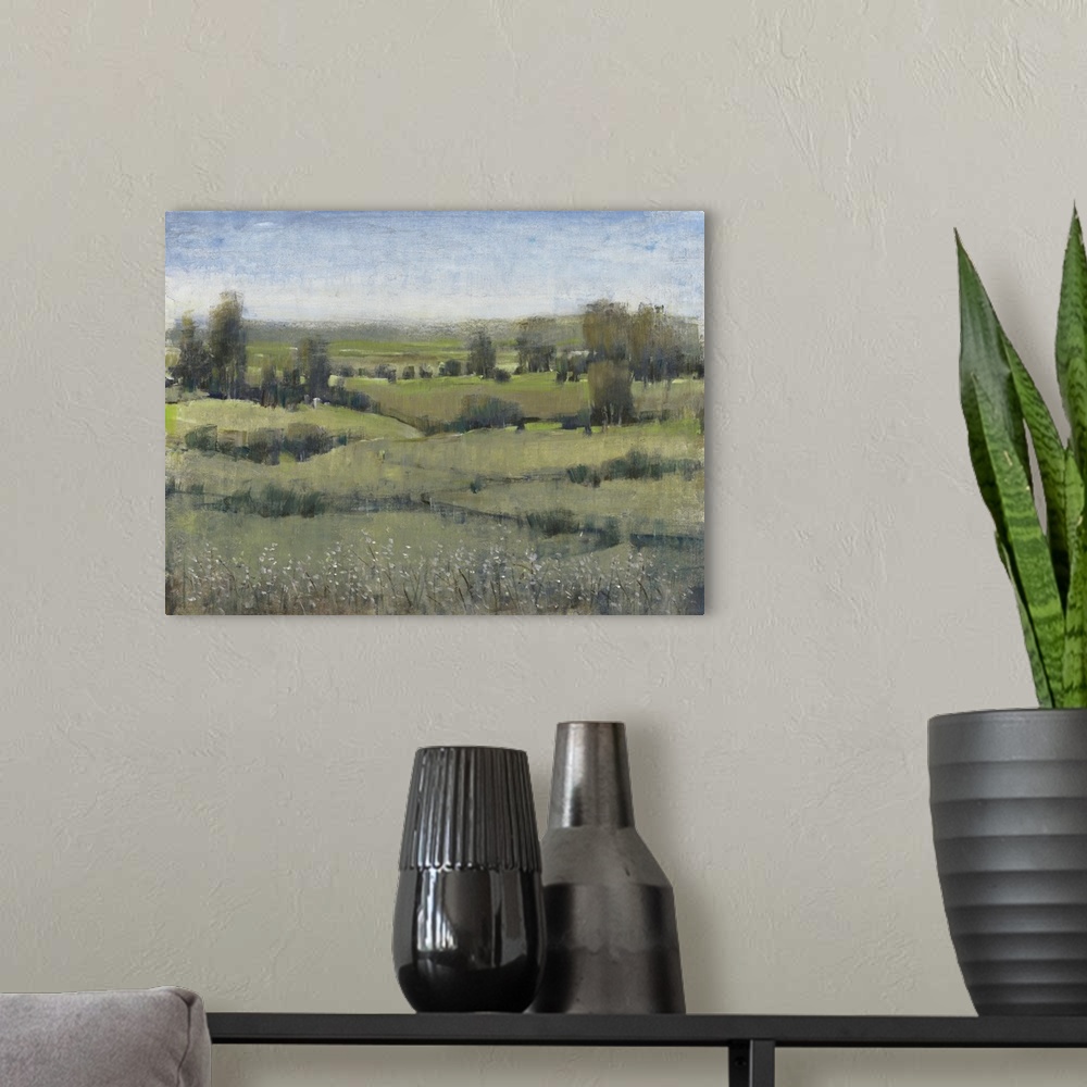 A modern room featuring Modern landscape artwork of verdant fields with trees under a blue sky.