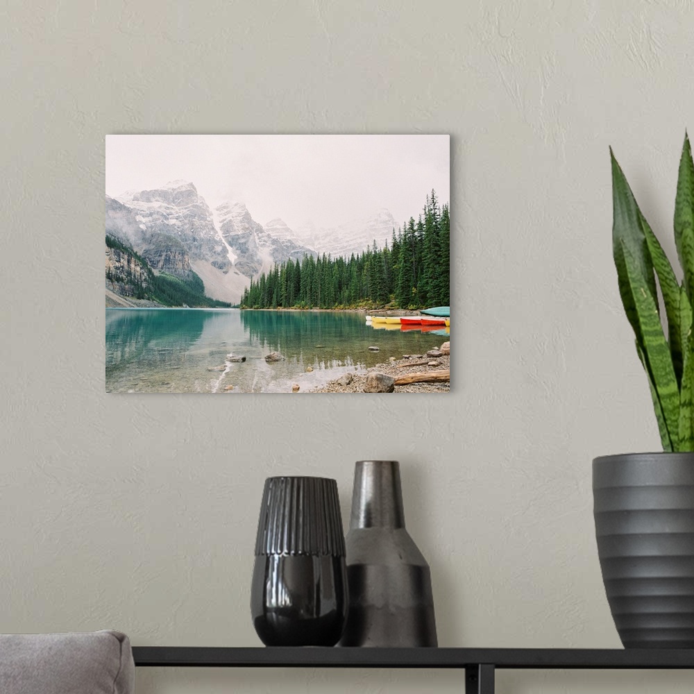 A modern room featuring A horizontal photograph of the mountains and trees reflected in Moraine Lake, Banff national park...