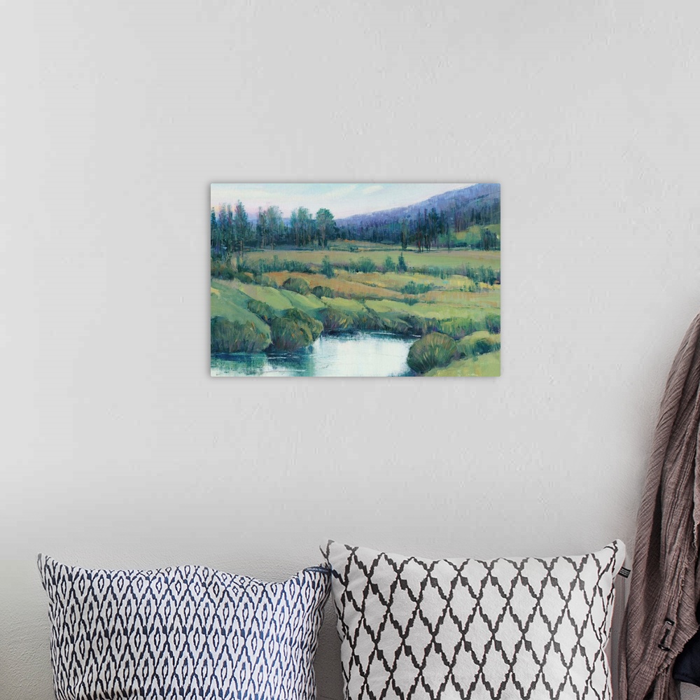 A bohemian room featuring Landscape painting of a tree lined meadow with a mountain range in the distance.