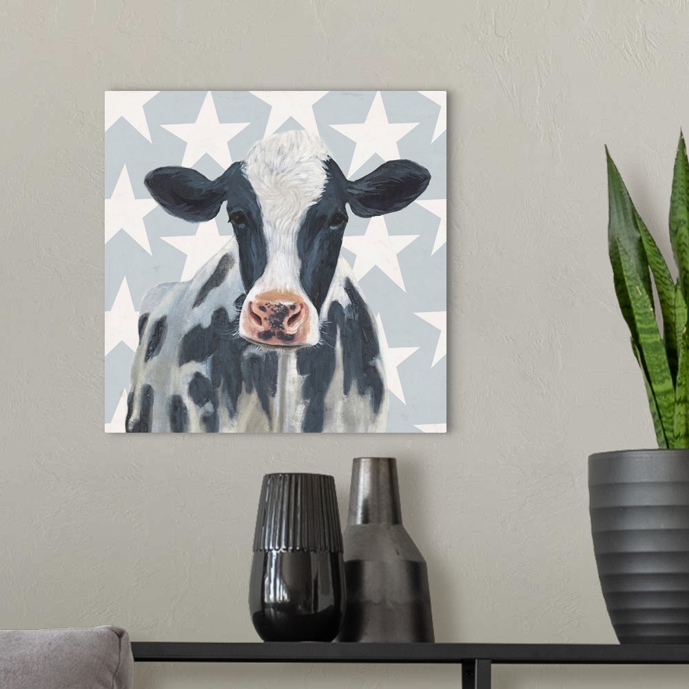 A modern room featuring Square painting of a black and white spotted cow on a gray and white star patterned background.