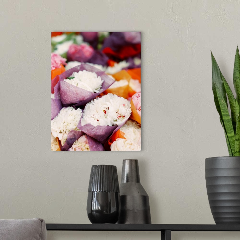 A modern room featuring Photograph of bunches of white peony flowers crapped in tissue paper in a market.
