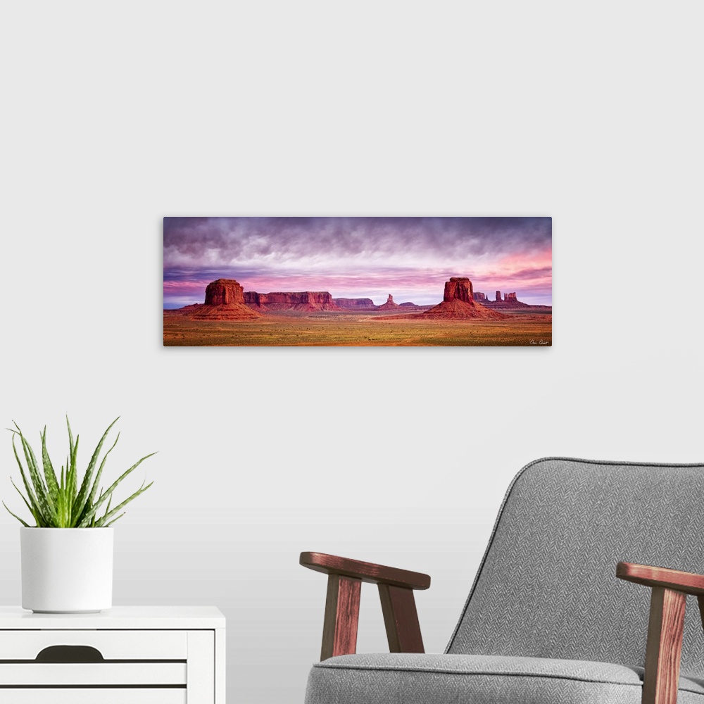 A modern room featuring Panoramic photograph of Monument Valley with a pink and purple sunrise above.