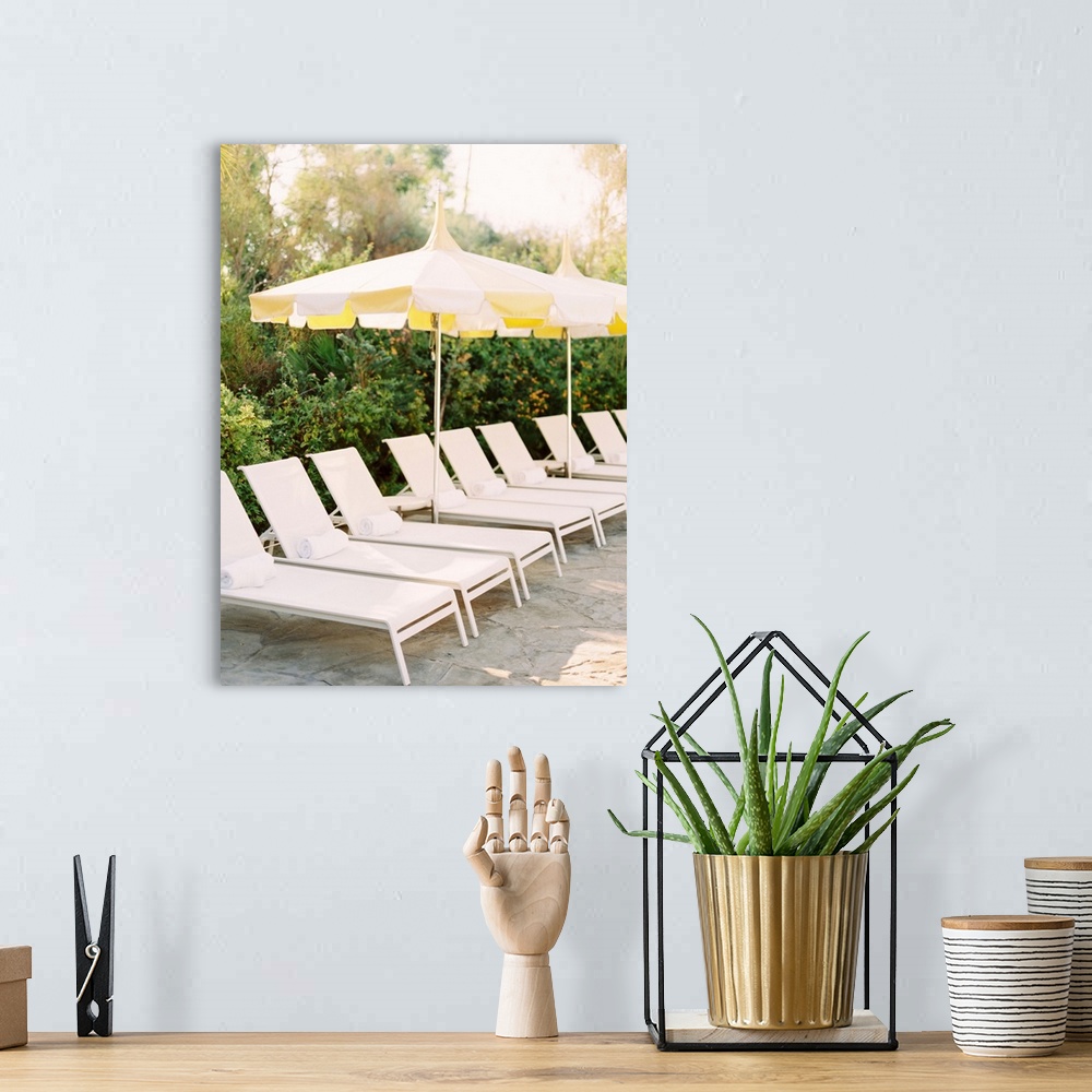 A bohemian room featuring A photograph of a neat row of pool loungers with rolled towels underneath yellow umbrellas.