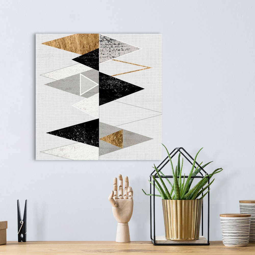 A bohemian room featuring Abstract art of two rows of triangles in black, grey, and gold.