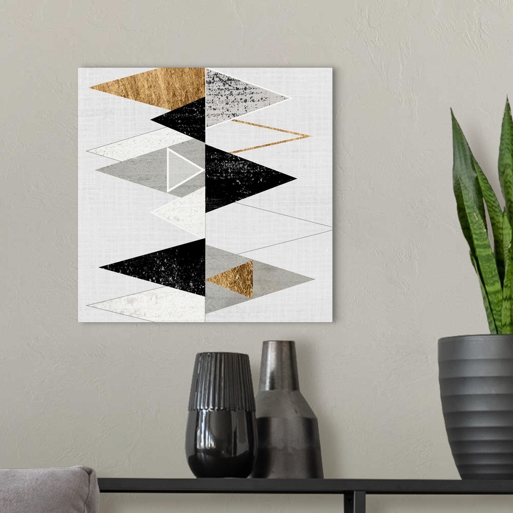 A modern room featuring Abstract art of two rows of triangles in black, grey, and gold.