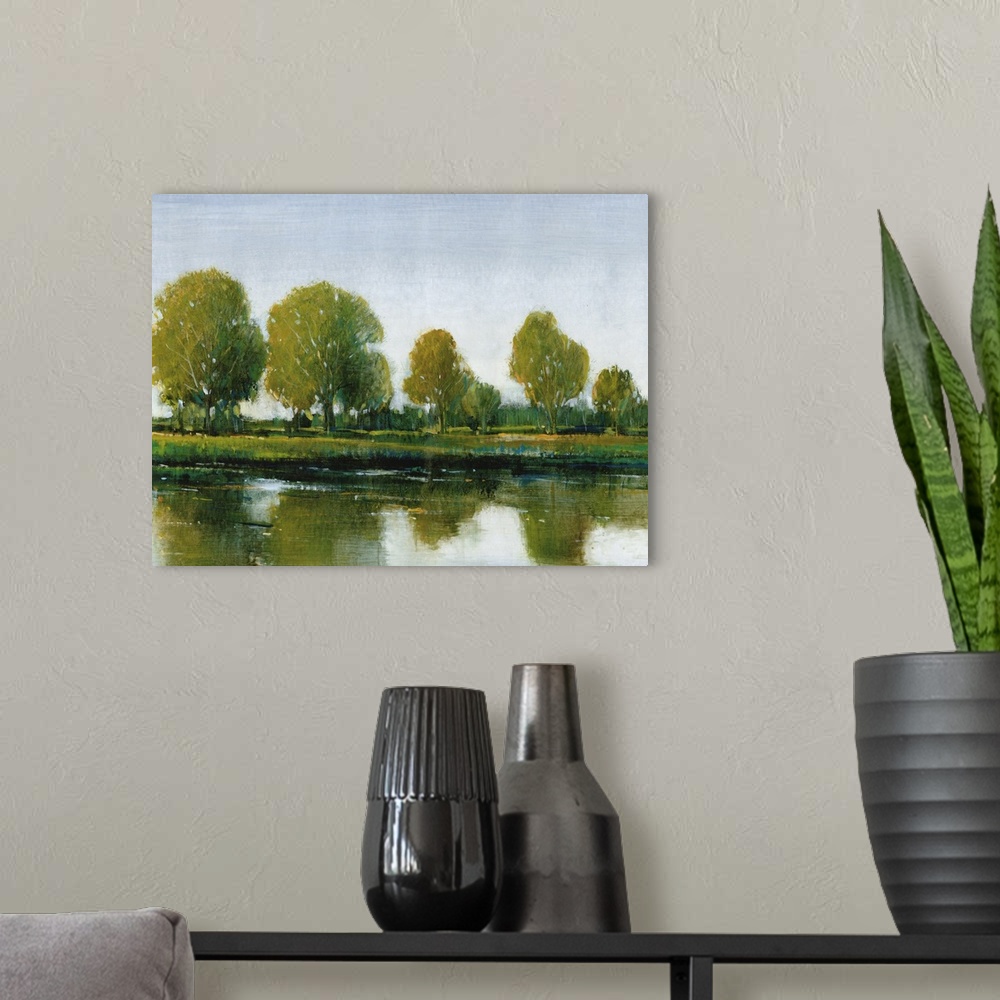 A modern room featuring Contemporary painting of an idyllic countryside scene of trees reflected in still water.