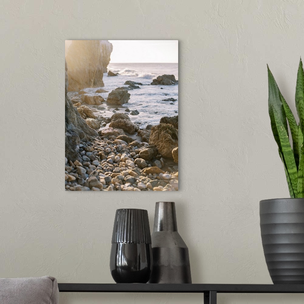 A modern room featuring A photograph of rocks and boulders at the edge of a rugged coastline at sunset.