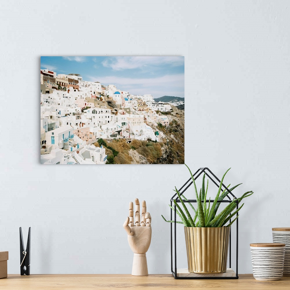 A bohemian room featuring Photograph of the iconic white buildings of Santorini, Greece perched on the hillside.