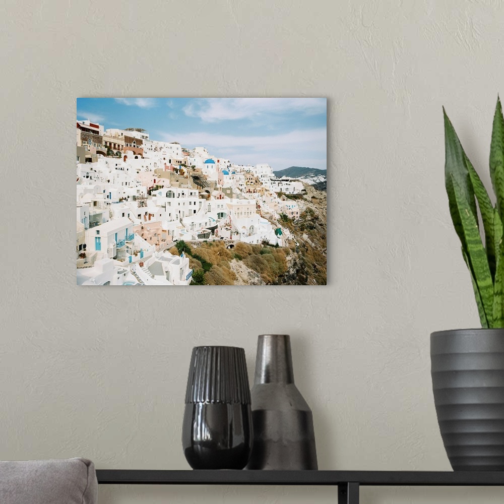 A modern room featuring Photograph of the iconic white buildings of Santorini, Greece perched on the hillside.