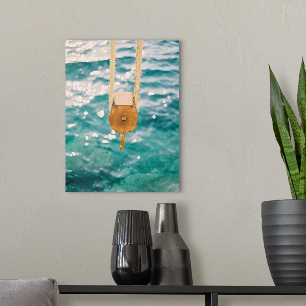 A modern room featuring Photograph of a tackle block hanging over the clear blue water, Santorini, Greece.
