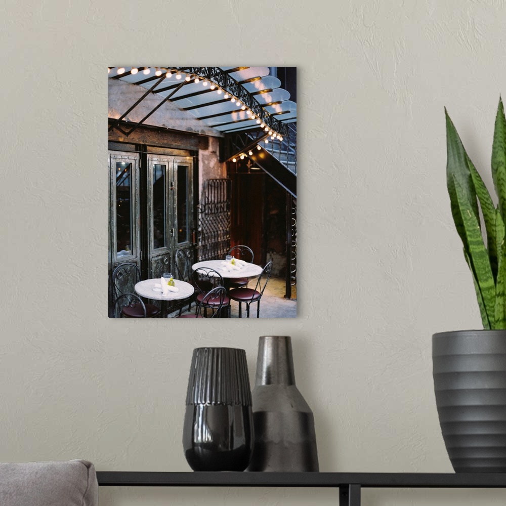 A modern room featuring A photograph of the tables and lights of a rustic mediterranean cafe.