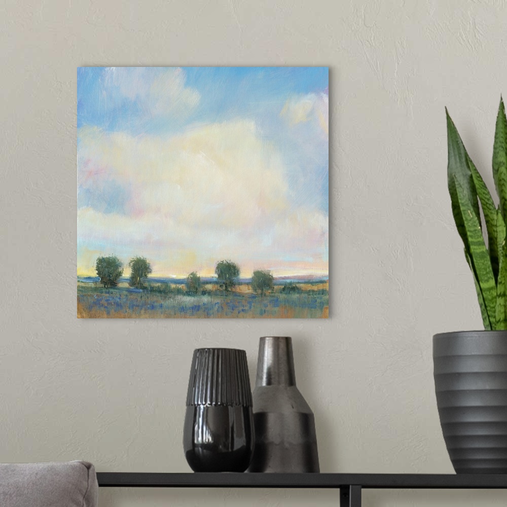 A modern room featuring Abstracted landscape painting with a field and trees below a cloudy, blue sky.