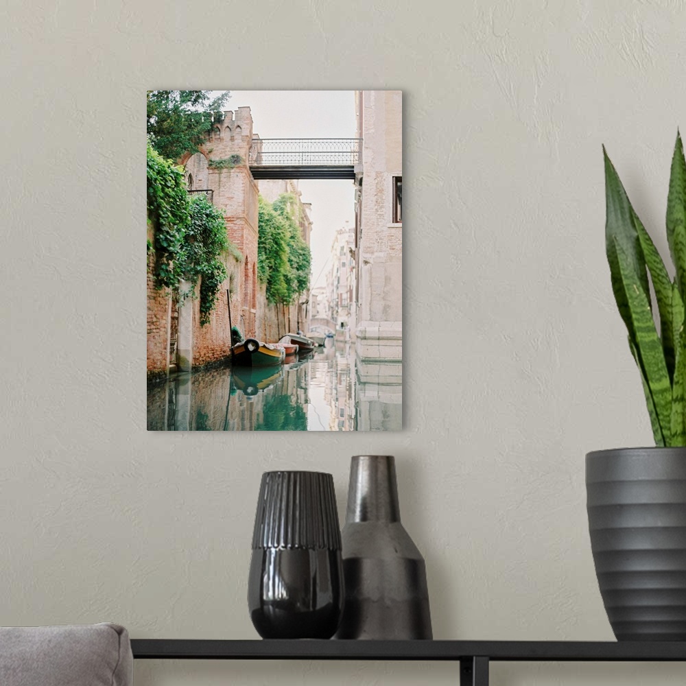 A modern room featuring Photograph of small boats moored beneath an old brick wall, Venice, Italy.