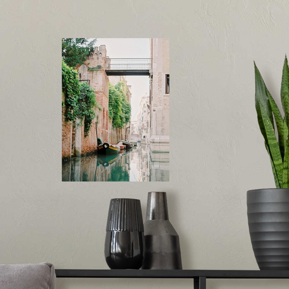 A modern room featuring Photograph of small boats moored beneath an old brick wall, Venice, Italy.